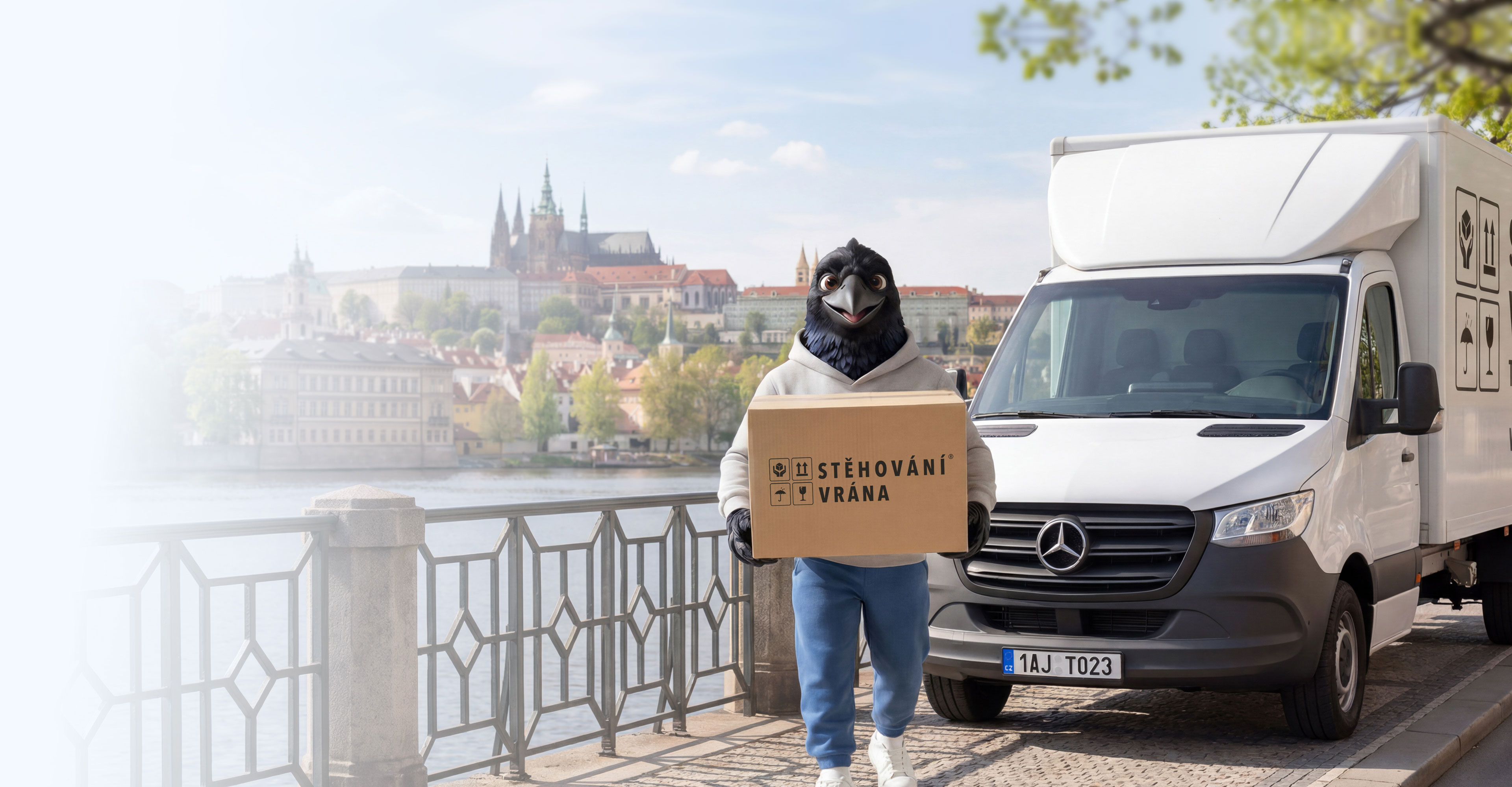 maskot Stěhování Vrána s firemní dodávkou na pražském nábřeží; Stehovanivrana.cz
